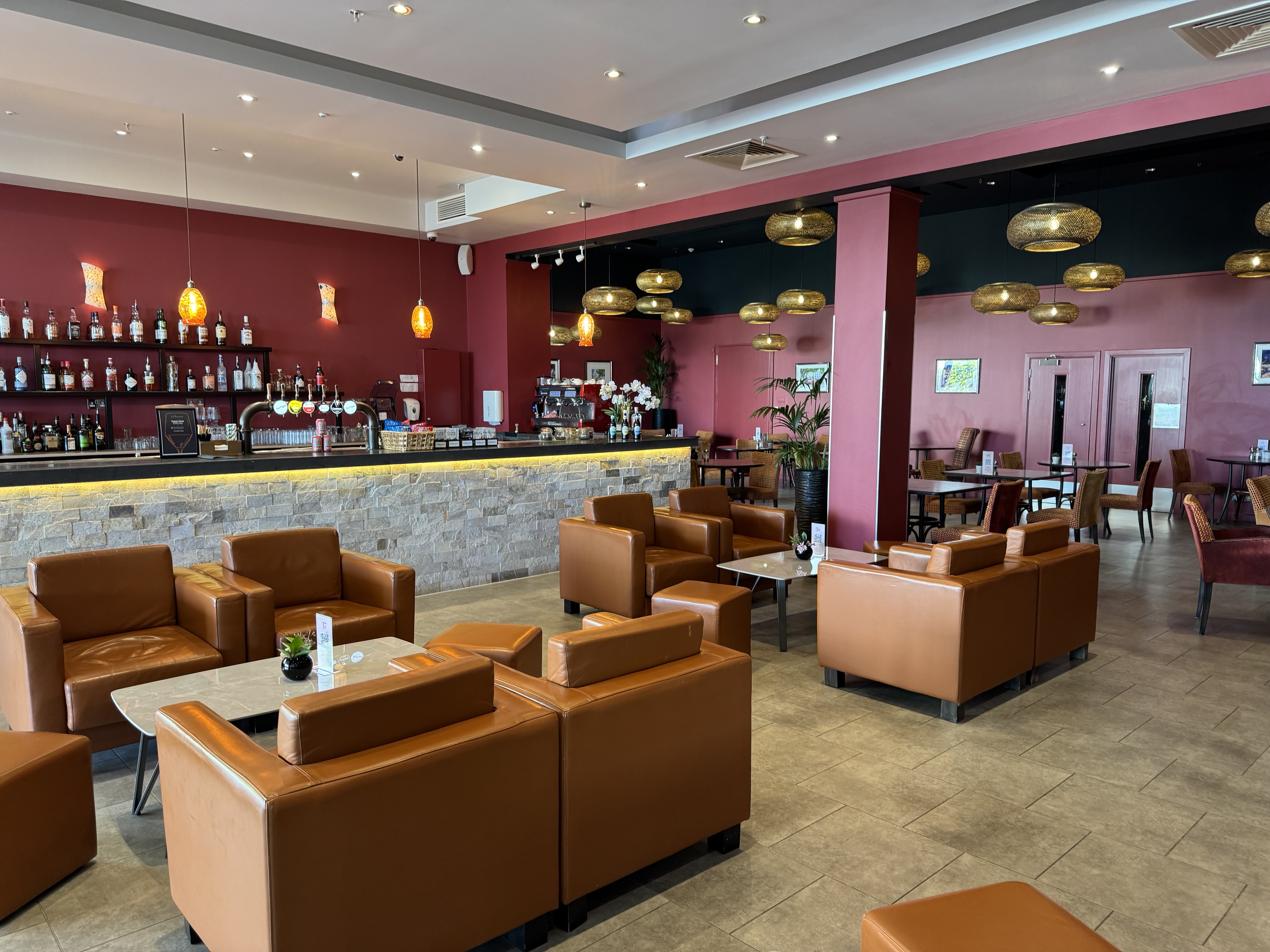 La Terrasse today — saturated red walls, black ceiling, tan leather club chairs and pendant lighting.